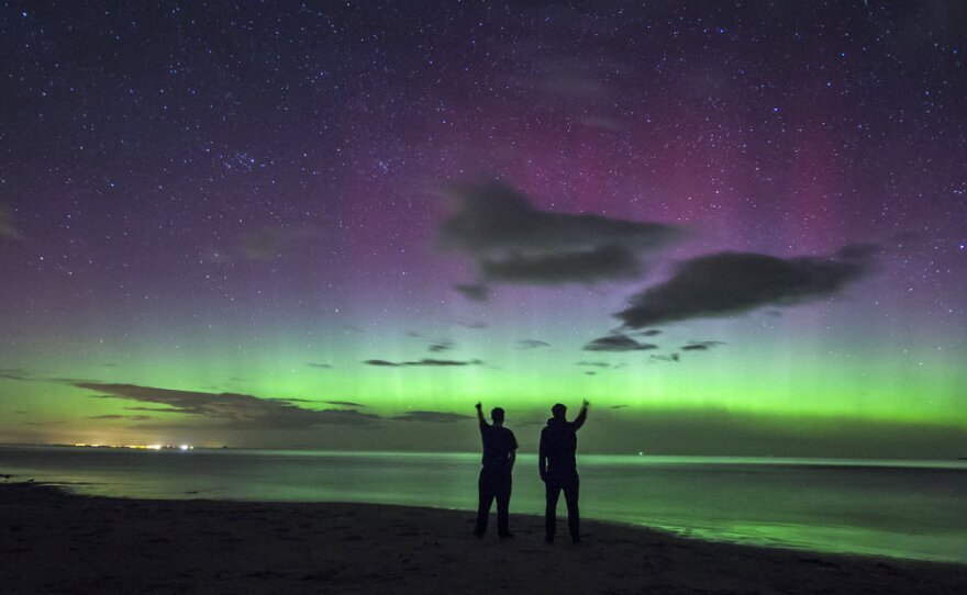 People view the Northern Lights over Bamburgh Castle Beach Thursday in Northumberland, England. The Aurora Borealis were visible farther south than usual, due to a powerful solar flare.