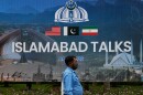 A police officer walks past a billboard regarding the United States and Iran negotiations, outside a media facilitation center in Islamabad, Pakistan, Saturday, April 11, 2026.