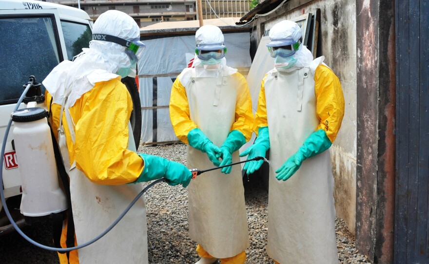 In a photo from Guinea's previous Ebola outbreak, medical staff clean their protection suits in March 2015 in Conakry, Guinea. Guinean authorities declared a new Ebola outbreak Sunday.