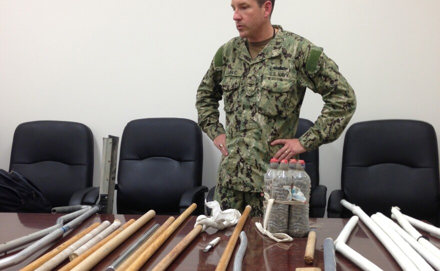 In this image reviewed by the U.S. military, Navy Capt. Robert Durand stands next to some of the makeshift weapons confiscated from detainees at the Guantanamo Bay prison following a clash Saturday between prisoners and guards.