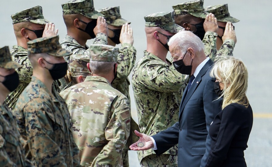 President Joe Biden holds a presidential challenge coin as he speaks with Air Force Mortuary Affairs Operations Air Force Col. Chip Hollinger and others after participating in a casualty return Aug. 29, 2021, at Dover Air Force Base.