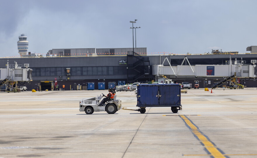 A Delta Air Lines employee drives an aircraft tug with a luggage cart between passenger concourses at the Hartsfield-Jackson Atlanta International Airport.