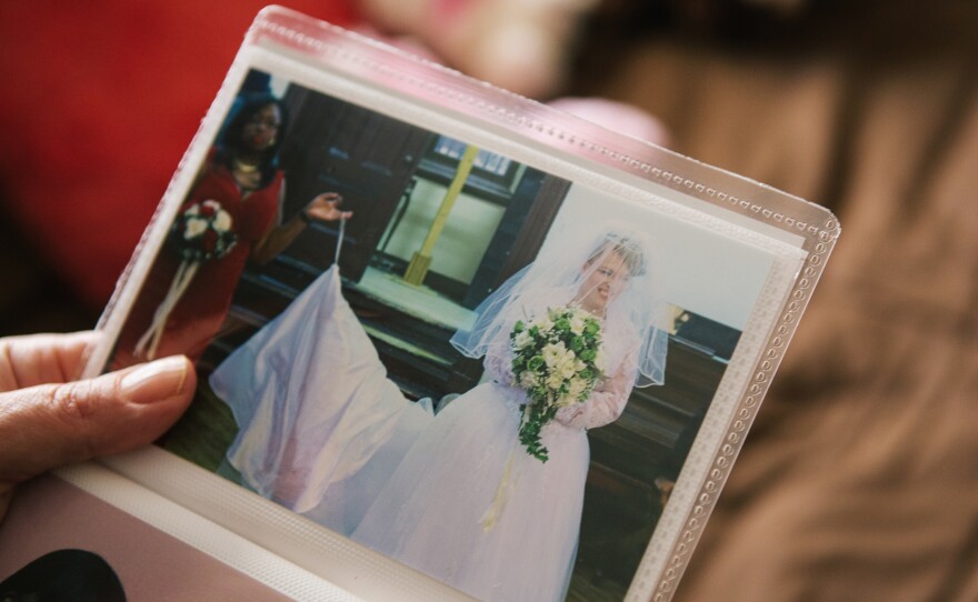 Pauline shows a photograph from her wedding day. After the wedding, her husband, David, moved into a room with Pauline in her caretaker's home. Now they talk on the phone most nights and David sends her cards to stay in touch.