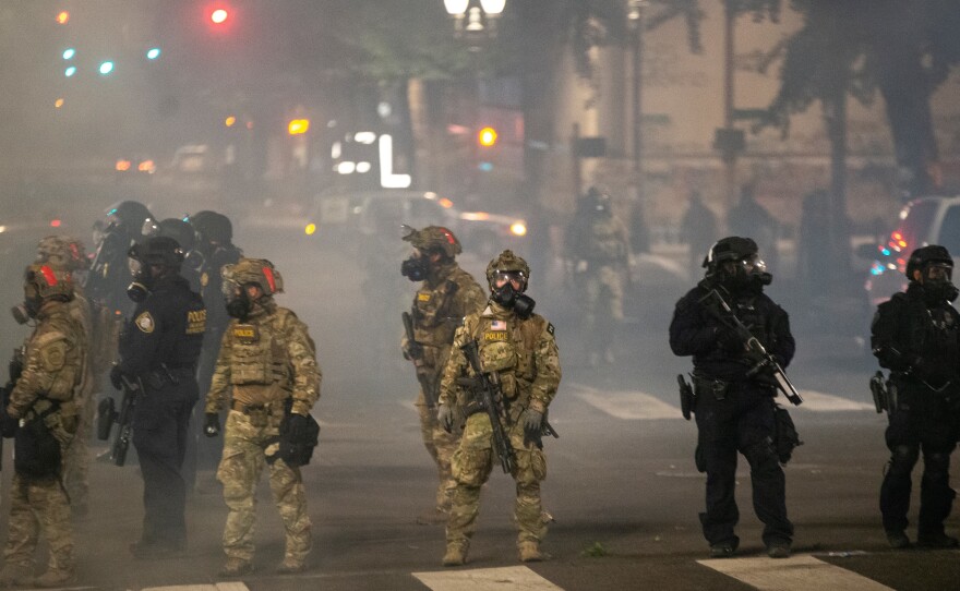 Federal police stand guard on Salmon Street after pushing protesters away from the Mark O. Hatfield U.S. Courthouse on Tuesday in Portland, Ore. The federal police response to the ongoing protests against racial inequality has been criticized by city and state elected officials.