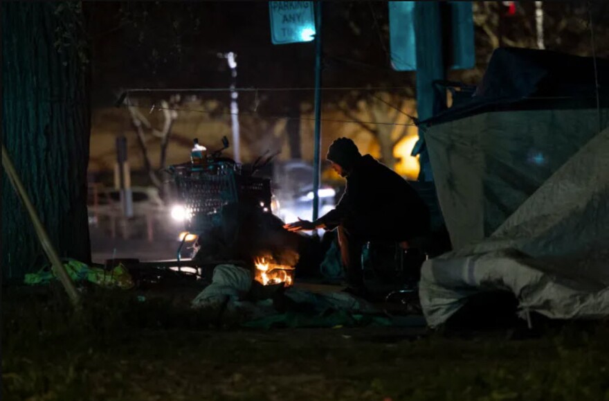 Muhammad, who declined to provide his last name, warms his hand at a fire near his tent in Sacramento, Calif. Undated photo.