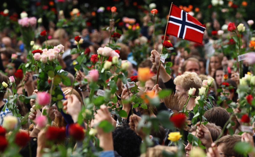 A Norwegian flag is held aloft Monday as people gather in Oslo's town center for a vigil following Friday's twin attacks in Oslo.