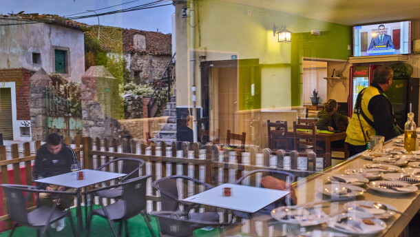 People seen through a window inside a bar in La Cabrera, on the outskirts of Madrid, Spain, watch a televised speech by Spanish Prime Minister Pedro Sanchez from La Moncloa Palace announcing national elections, Monday, Oct. 5, 2026.