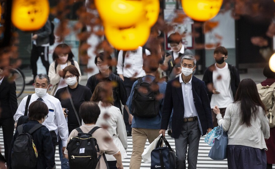 People in Tokyo wear masks on May 7. Daily coronavirus infections in Japan's capital have topped 4,000 — nearly four times as many as a week ago.