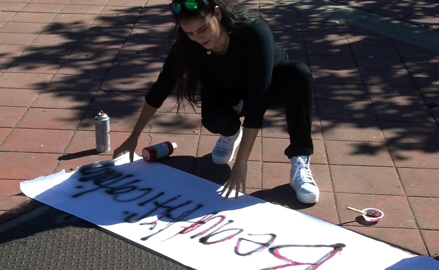 A resident works on a banner during an informal protest against removing benches and planters at the corner of Euclid and Imperial avenues in San Diego, Oct. 31, 2015.