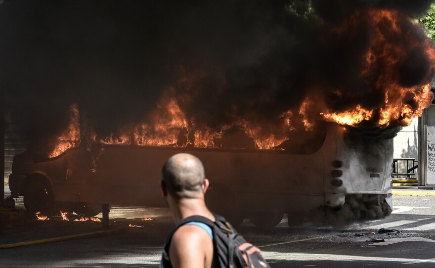 A man stares at a burning bus in Caracas on Saturday. Hundreds of people have been injured in the weeks of near-constant clashes between protesters and police.