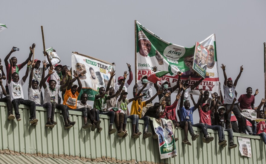 Supporters stand on a roof with placards and banners as they attend a campaign rally of the Nigerian opposition leader Atiku Abubakar on Thursday in Jimeta, eastern Nigeria.