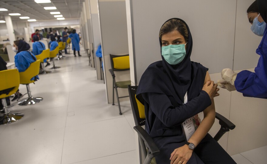 A female medical worker wearing a protective face mask receives a dose of the China's Sinopharm vaccine on the third day of mass general COVID-19 vaccinations in a shopping center on May 17 in Tehran.