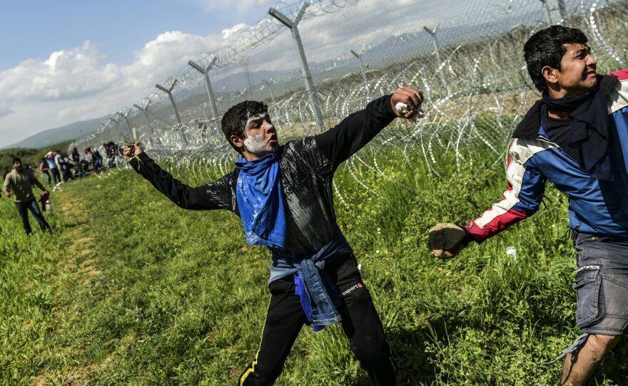 Refugees and migrants clash with Macedonian soldiers as they storm the border fence near Idomeni on Sunday.