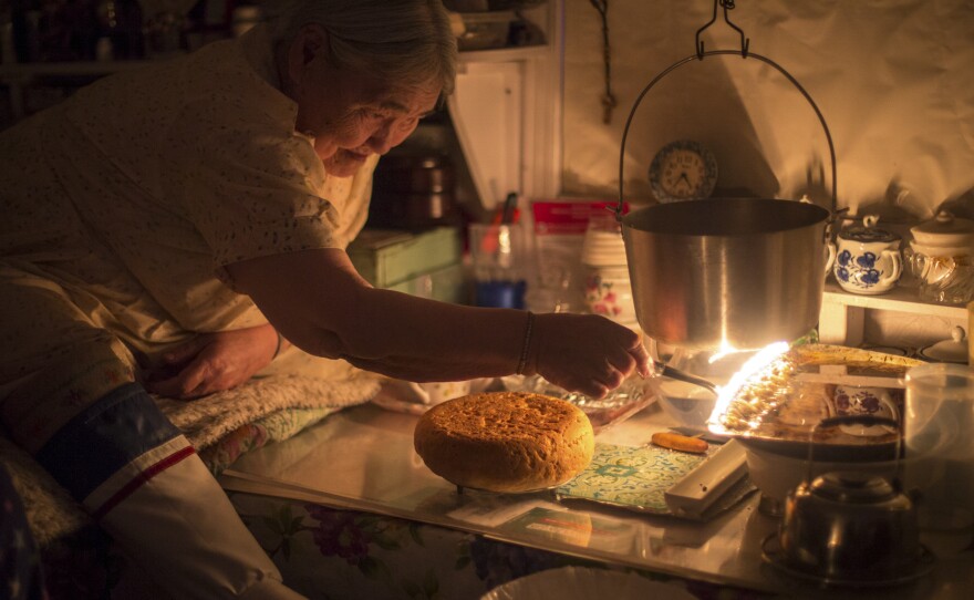 Qaapik Attagutsiak, 94, the eldest member of the community of Arctic Bay, bakes a loaf of bannock — traditional bread — over the heat of a seal oil lamp called a qulliq. These lamps were once the most important possession in any Inuit home, providing light and warmth. Although few people still use them today, they remain a symbol of Inuit culture and family.