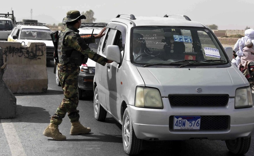 An Afghan National Army soldier searches a vehicle at a checkpoint in Kandahar, Afghanistan, Thursday on the way to the Maiwand army base, the site of the Taliban attack late Wednesday.