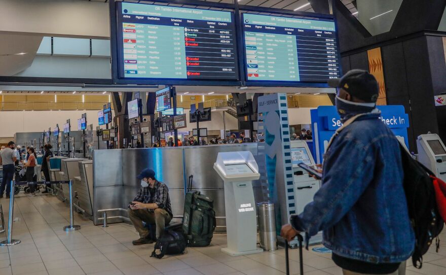 A passenger holds his mobile phone while looking at an electronic flight notice board displaying canceled flights at OR Tambo International Airport in Johannesburg, South Africa.