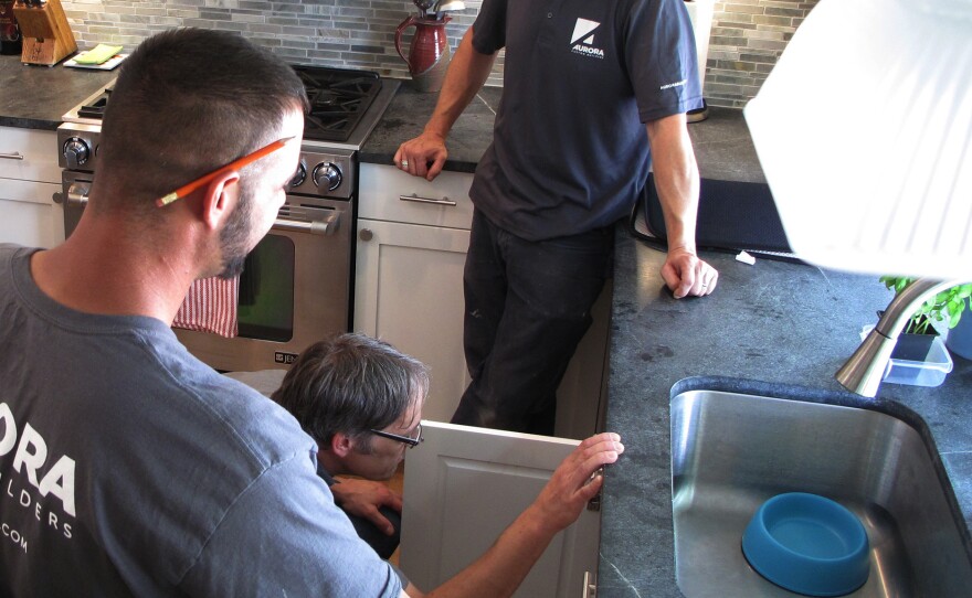 Nathaniel May (under sink) and his crew with Aurora Custom Builders goes through the final check list on a kitchen renovation outside Boston.