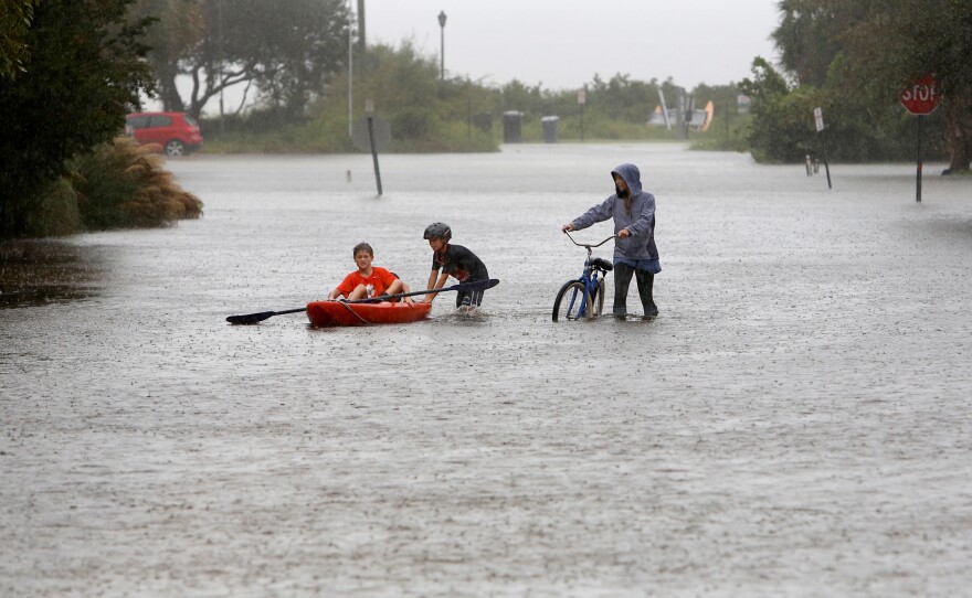 Will Cunningham, 14, rides his bike down Station 29 on Sullivan's Island, S.C., with his friend Patrick Kelly, 14, going the kayak route during flood waters on Sullivan's Island Saturday, on Saturday.