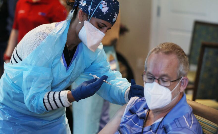 A health care worker with the Florida Department of Health administers a Pfizer-BioNtech COVID-19 vaccine at a retirement community in Pompano Beach, Florida. New Trump administration guidance is expected Tuesday, urging states to make all people over 65 eligible for the vaccine.