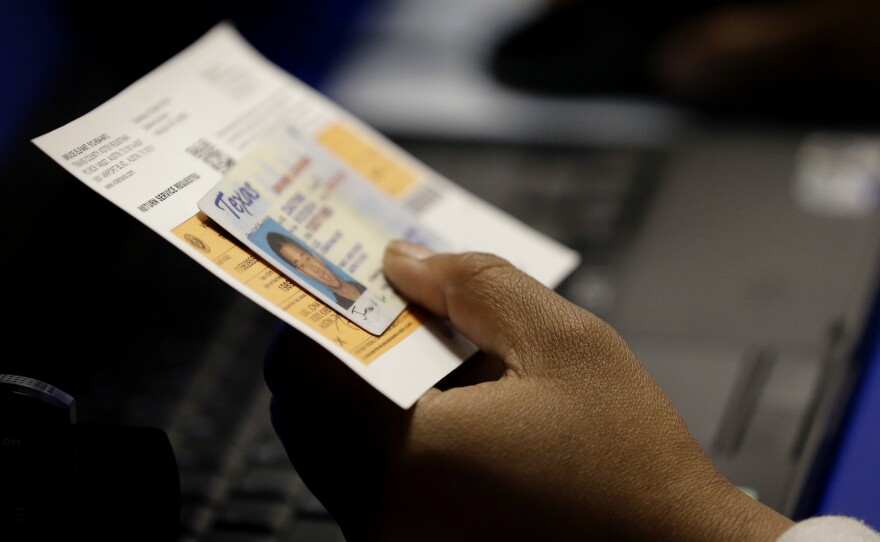 An election official checks a voter's photo identification at an early voting polling site in Austin, Texas.