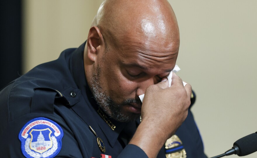 U.S. Capitol Police Pfc. Harry Dunn wipes his eye as he testifies during Tuesday's House select committee hearing on the Jan. 6 attack. During his testimony, Dunn said rioters hurled racial epithets at him and other Black officers.