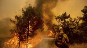 A firefighter scrambles to stop the Pawnee fire as it spots across Highway 20 near Clearlake Oaks, Calif., on Sunday, July 1, 2018.