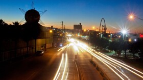 Car headlights streak through the Tijuana 22000 landscape at dusk.