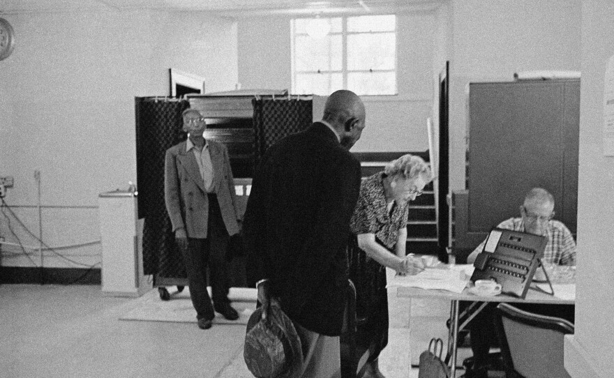 As James Hadden (left) leaves a voting booth, Percy Knighten checks in to vote in Lake Providence, La., on July 28, 1962. The two men, along with Mary Johnson, became the first African Americans to cast a vote in East Carroll Parish since 1922.