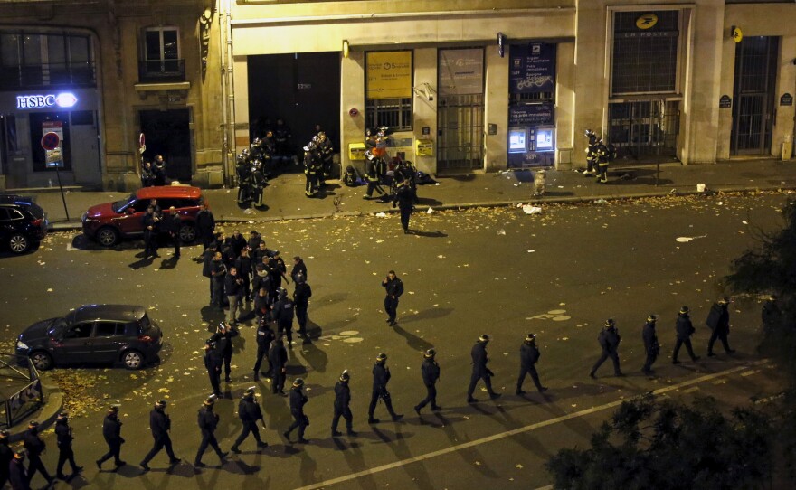 French police with protective shields walk in line near the Bataclan concert hall.
