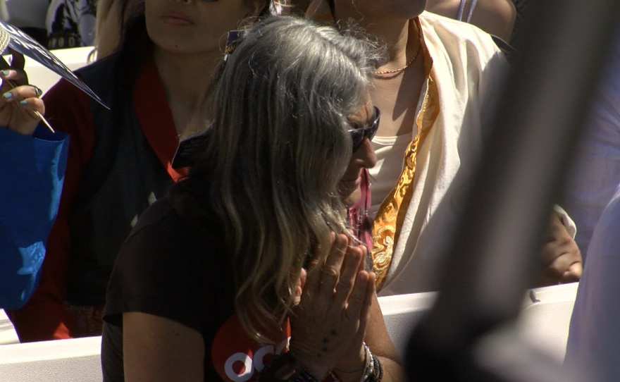 A woman holds her hands together in a prayer position during the Dalai Lama's visit to UC San Diego, June 16, 2017.