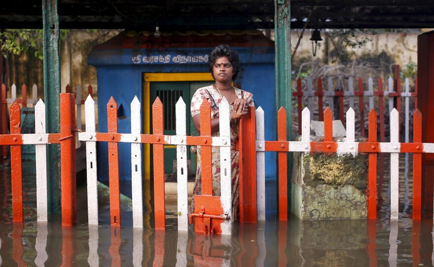 A woman stands outside a submerged temple on Friday.