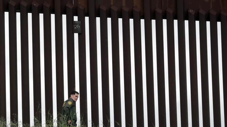 A border patrol agent walks along a border wall separating Tijuana, Mexico, from San Diego in March 2020. The Trump Administration has proposed a number of changes that would restrict asylum claims.