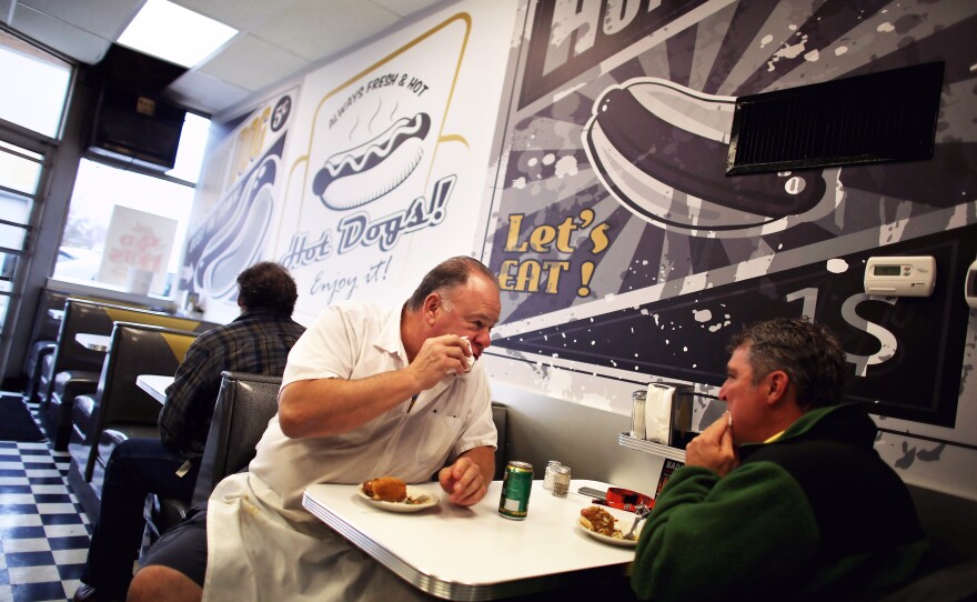 Harlan eats a Coney with a customer.