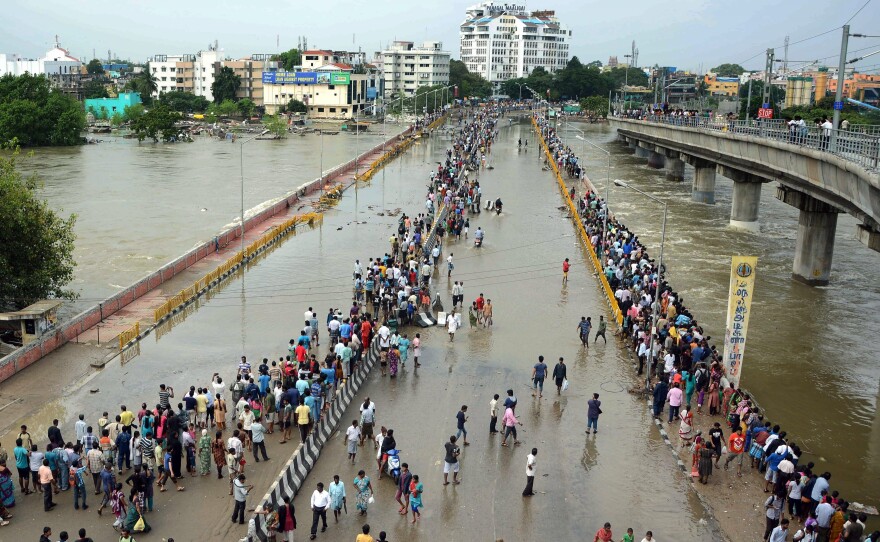 Indian residents attempt to cross a waterlogged highway in Chennai on Thursday.