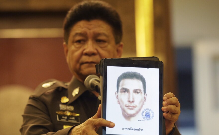 Police spokesman Lt. Gen. Prawuth Thavornsiri shows a photo of one of three men for whom Thai authorities have issued new arrest warrants in connection with the bombing case.