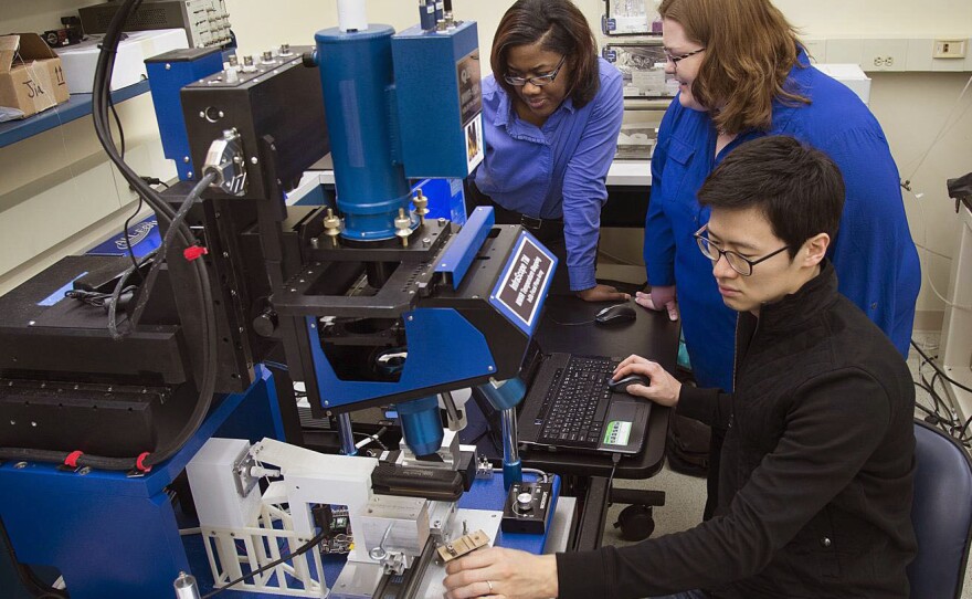 Tahira Reid and Amy Marconnet work with Purdue University graduate student Jaesik Hahn, using an infrared microscope, to study how heat affects hair.