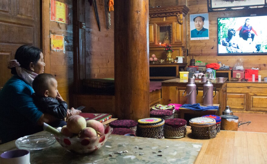 Zhaba Songding's mother Cili Zhuoma and his son, Luosang Nima, watch television at home.