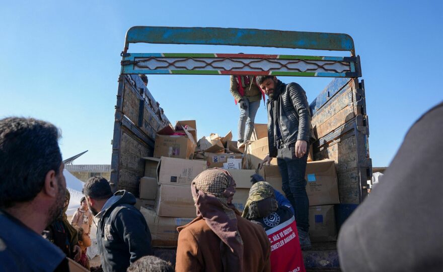 People receive aid at a make-shift shelter near the rebel-held town of Jinidayris, Syria.