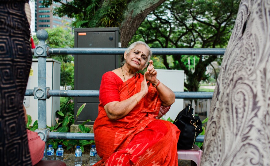 Indian dance pioneer Santha Bhaskar demonstrates a scene depicting the beauty of nature, petting a bird, for her daughter and granddaughters. She shows them the dance gestures and expressions as she prepares to perform for a government event.