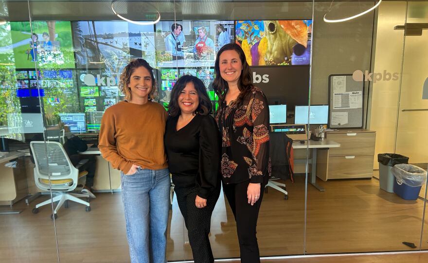 The image is a photograph of Lilly Ribner, Martha Rañón, and Shannon Patel at KPBS on December 1, 2025.