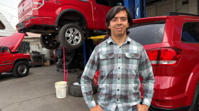 Guadalupe Higuera stands in front of trucks being repaired at his family's shop in Phoenix.