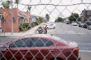 A man transports his belongings in a shopping cart on the city's side of a chain link fence in San Diego on Friday, Aug. 15, 2025.
