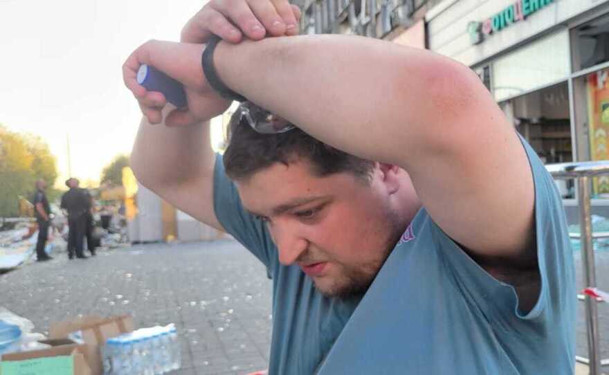 Maksym Budko demonstrates how he covered his head after being thrown to his knees by the blasts of two cruise missiles that struck as he was using an ATM in Vinnytsia.