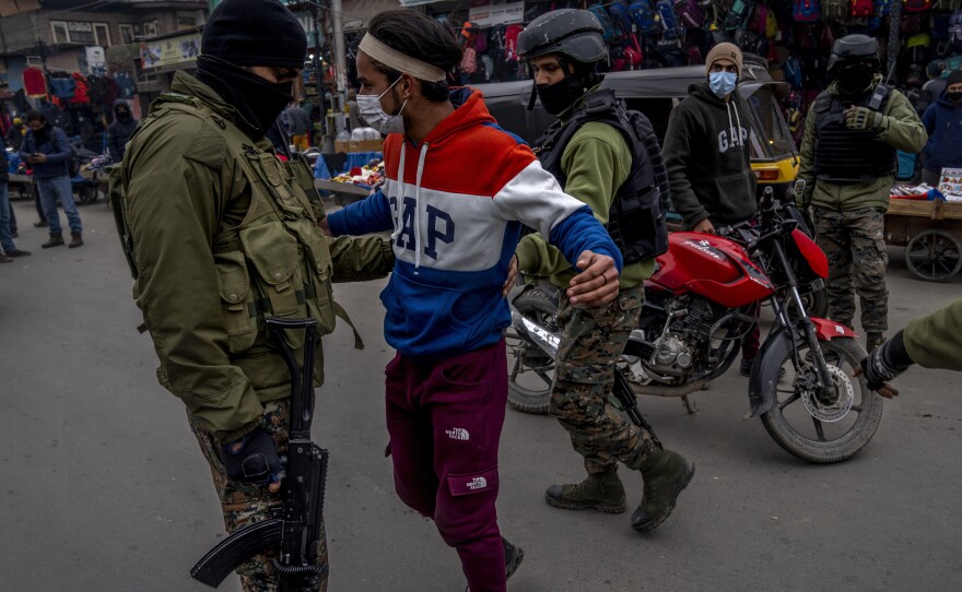 Indian paramilitary soldiers frisk a Kashmiri during a surprise check operation in Srinagar, on Jan. 18, 2022.