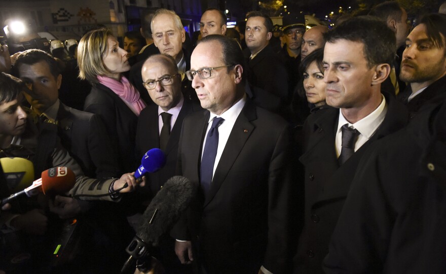 French President Francois Hollande (center), flanked by French Interior Minister Bernard Cazeneuve (left) and French Prime Minister Manuel Valls (right), addresses reporters near the Bataclan.