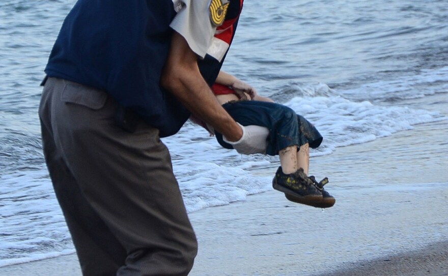 A Turkish police officer carries Aylan Kurdi's dead body off the shores in Bodrum, southern Turkey, on Sept. 2.