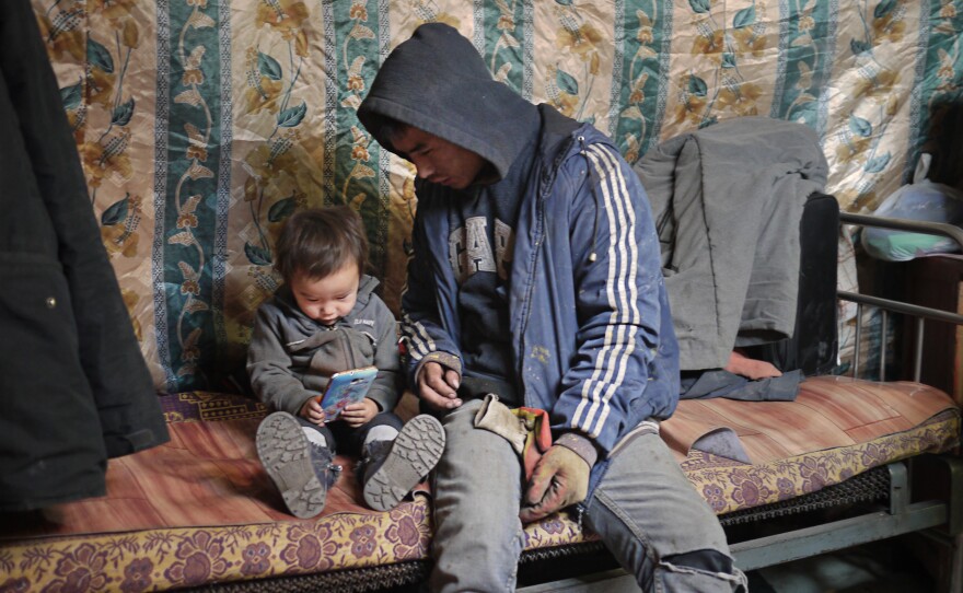 One of the members of a coal mining brigade spends a moment with his two-year-old son before descending into a mine shaft.