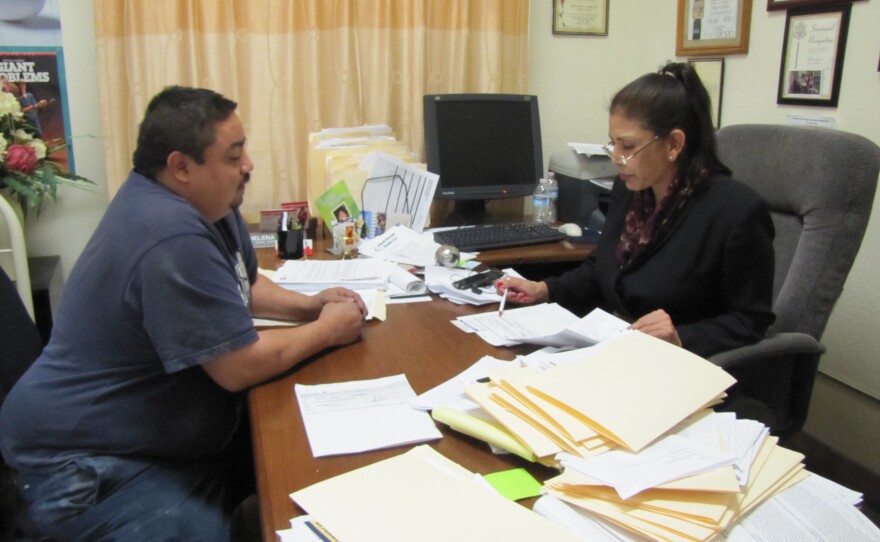 Helena Garcia looks over paper work with Fernando Terriquez in her office. Terriquez has seen Garcia help other immigrants get back money they are owed, so asked for her help getting proper payment from his employer.
