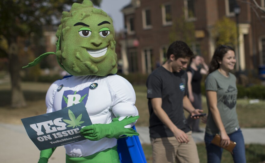 Buddie, the mascot for the pro-marijuana legalization group ResponsibleOhio, waits on a sidewalk to greet passing college students during a promotional tour bus at Miami University of Ohio last month.