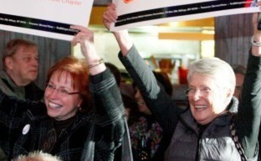 Billings Library Foundation Board President Evelyn Noennig (left) and Suzanne McKiernan arrive at a bar carrying signs to support an initiative for a library bond, as patrons gathered to watch election results.